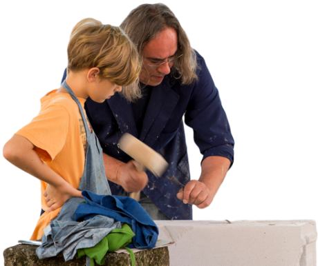 Utrinek iz počitniških dejavnosti: Izkušeni učitelj-kipar demonstrira mlademu učencu kako se uporablja dleto in kladivo za rezbarjenje lesa.